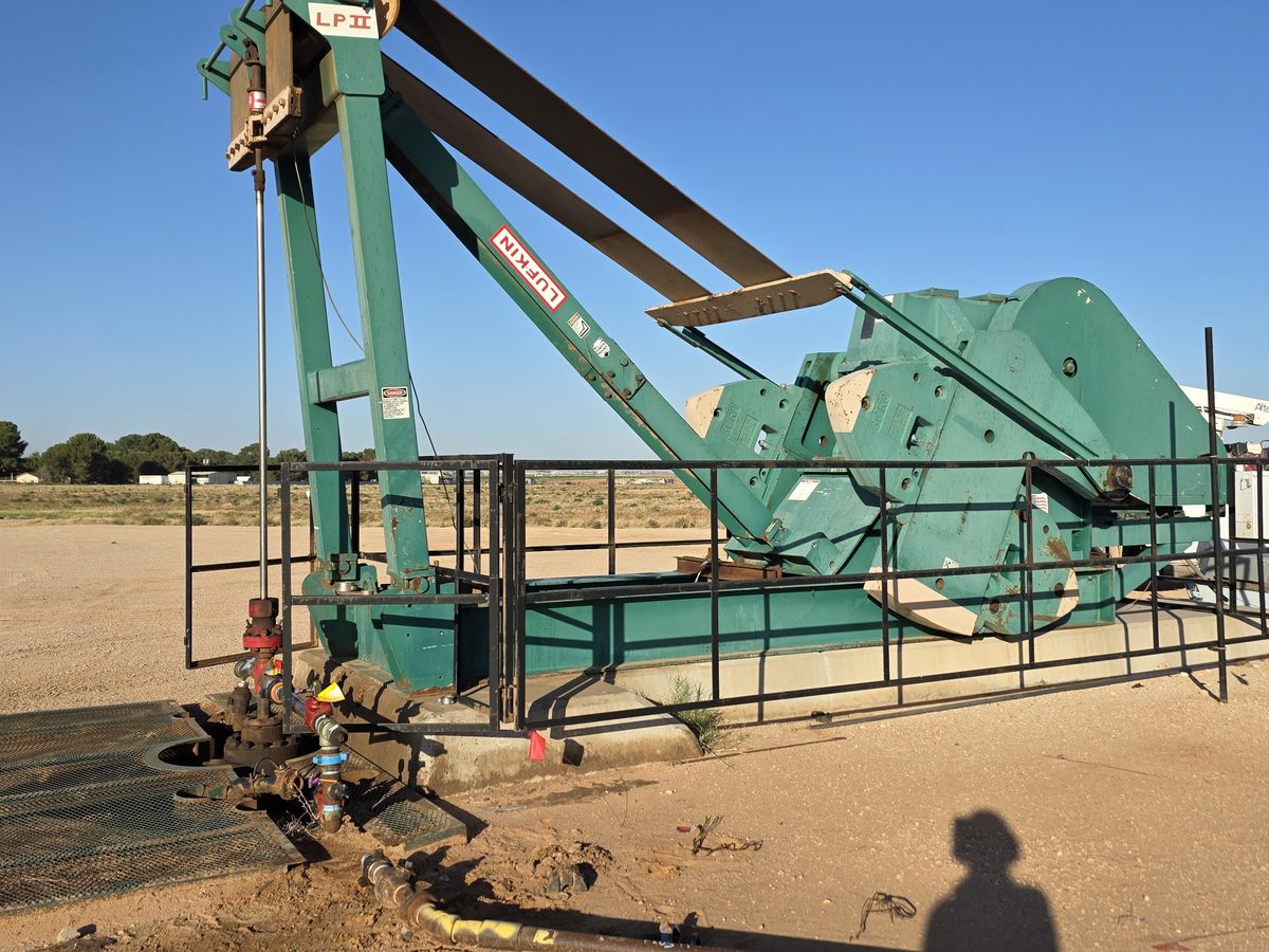 Green Lufkin LP II low-profile pumping unit behind its safety rail